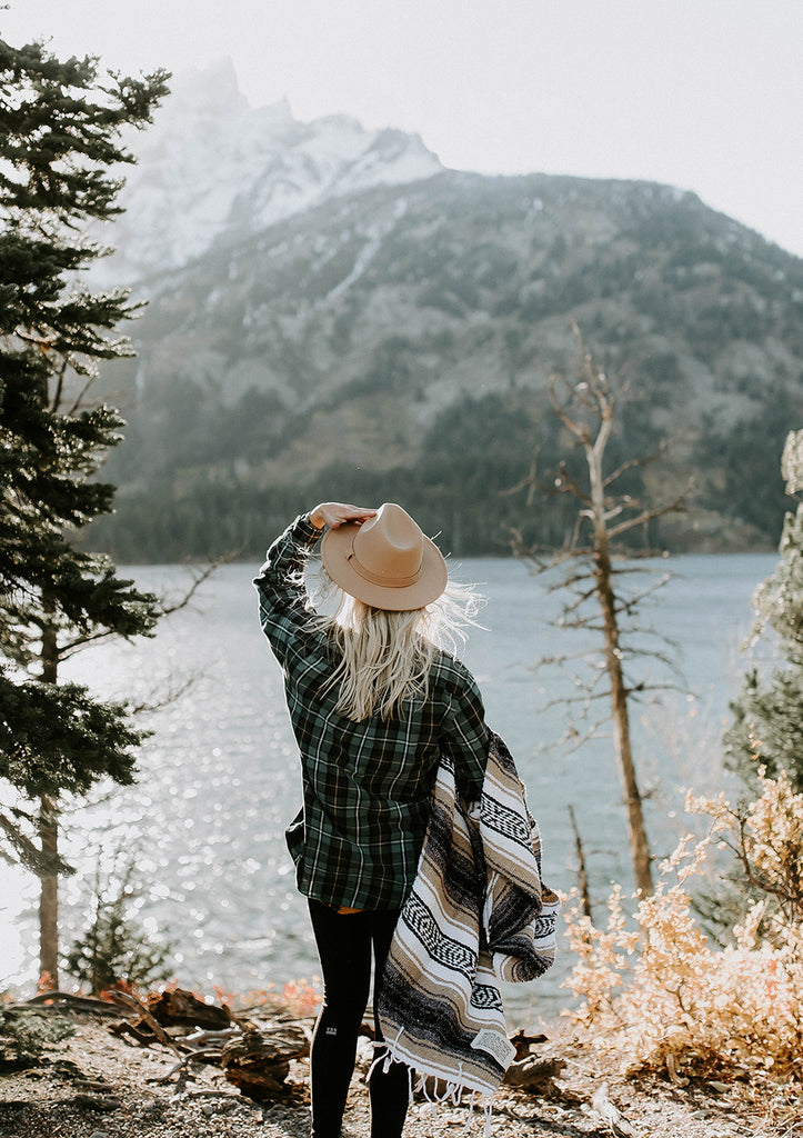 Woman overlooking a mountain with a Campo Mexican blanket. Get adventure ready with a falsa blanket of your own by Mntn & Moon